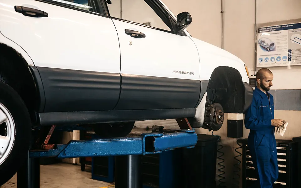 Mechanic working beside a car raised on a lift in a repair shop