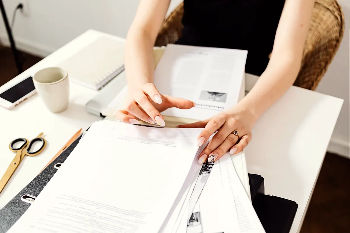 Hands organizing a stack of printed documents at a desk