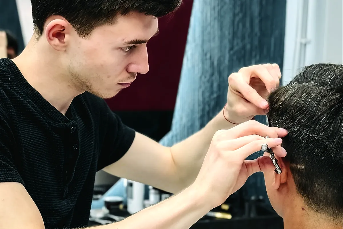 Barber trimming a client's hair with scissors