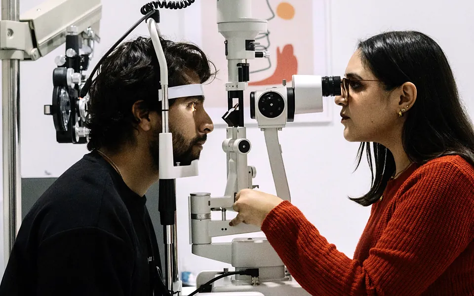 Optometrist examining a patient with a slit lamp in an exam room
